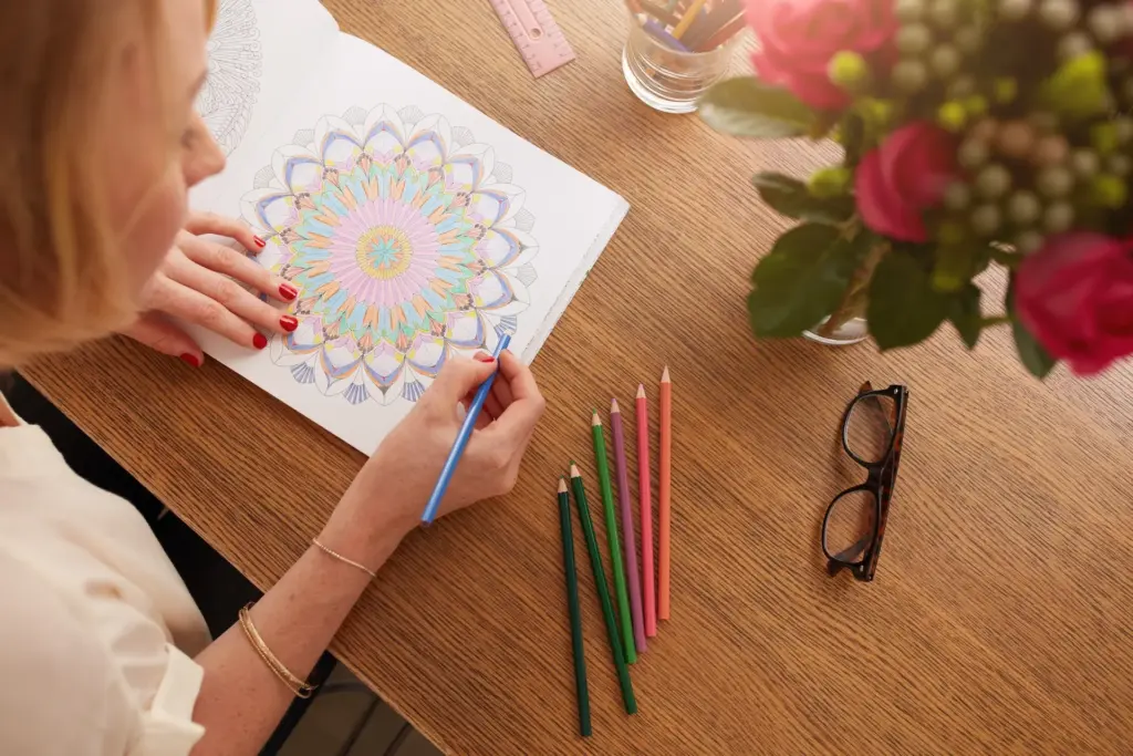 Female drawing in adult coloring book at home