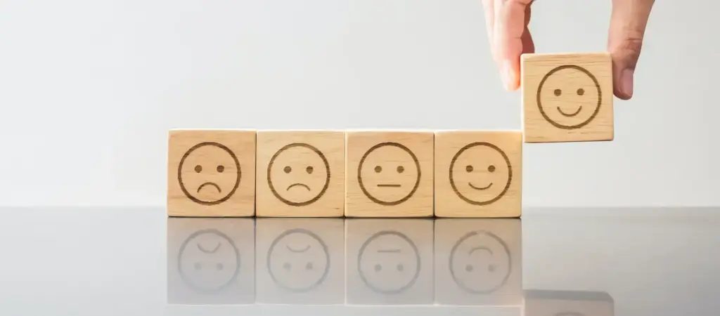 Man hand holding emotion face block. Customer choose Emoticon for user reviews.