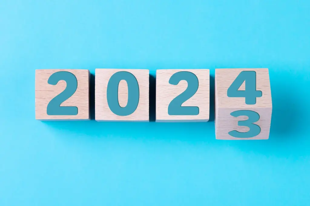 2024 Happy New Year. Wooden cube block 2024 from 2023 to 2024 on blue. Concept 2024 New Year