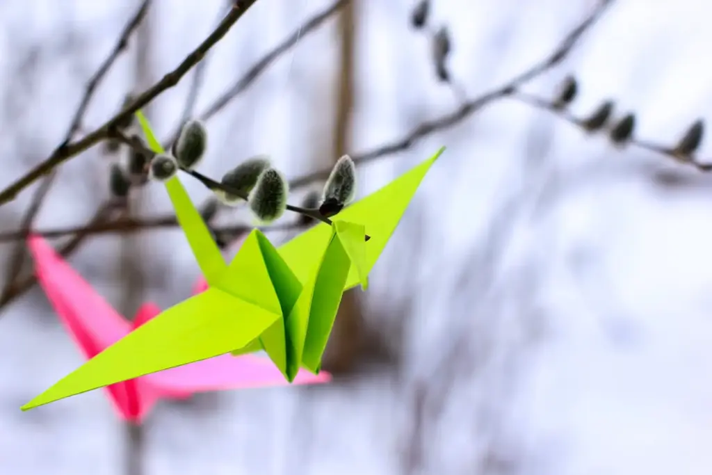 Bright origami paper cranes on the branches of a willow. The concept of hope, happiness, peace.