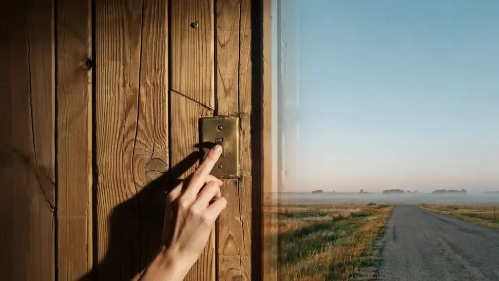 A hand presses a light switch on a wooden wall, which transitions into an open landscape with a rural road and fields under a clear sky. STG-Health